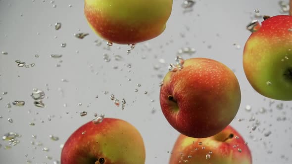 Fresh Fruits Apples Red and Yellow Falling in Water Spinning and Rotating with Air Bubbles