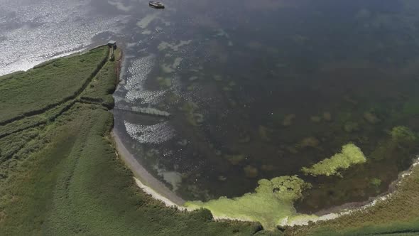 Tracking aerial across the fleet lagoon at the Abbotsbury Swannery. A patch of green surface algae h