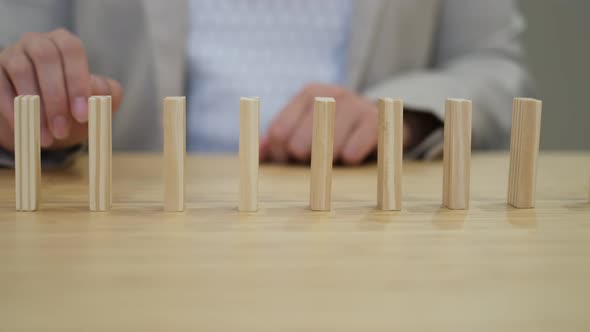 Businessperson Hand Stopping Colorful Blocks From Falling on Table in Office