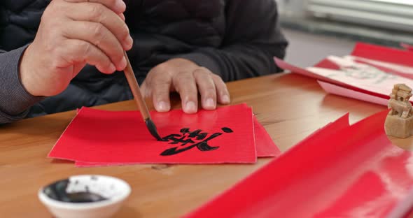 Man write on red paper in chinese for lunar new year, word means luck