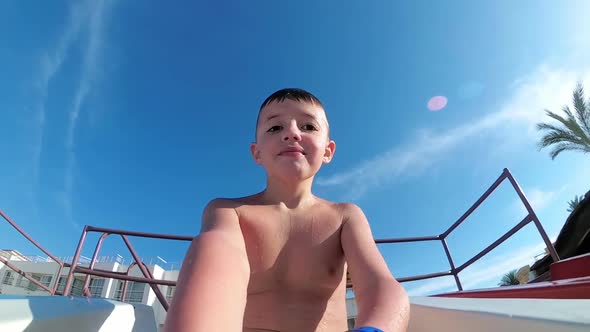 Happy Boy Slides Down a Water Slide and Takes a Selfie with Himself at a Hotel in Egypt. Slow Motion