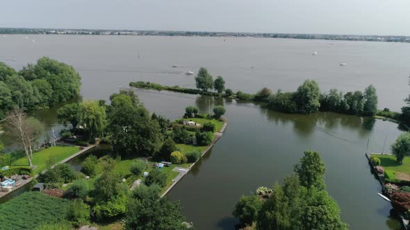 Aerial Slomo shot of Green Dutch Countryside with Small Boats and Lake, during Sunny Weather and Sma