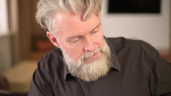 close-up of the face of a solid bearded gray-haired man who plays the piano