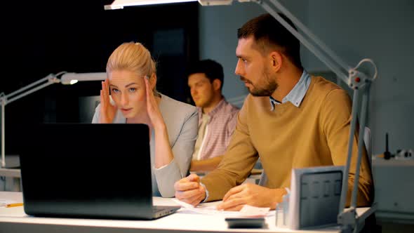 Business Team with Laptop and Files at Dark Office