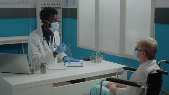 Doctor with Face Mask Consulting Disabled Woman at Desk