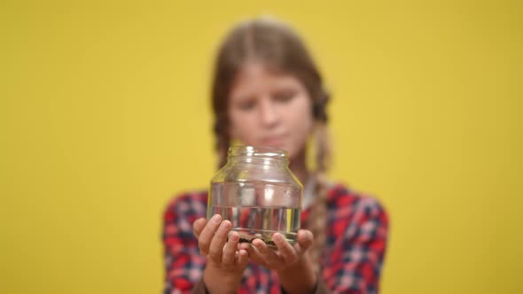 Catfish Swimming in Aquarium Bottle with Blurred Teenage Girl at Yellow Background