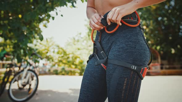 Sporty Woman Putting on Belaying Harness Before Climbing Practice at Outdoor Gym Close Up