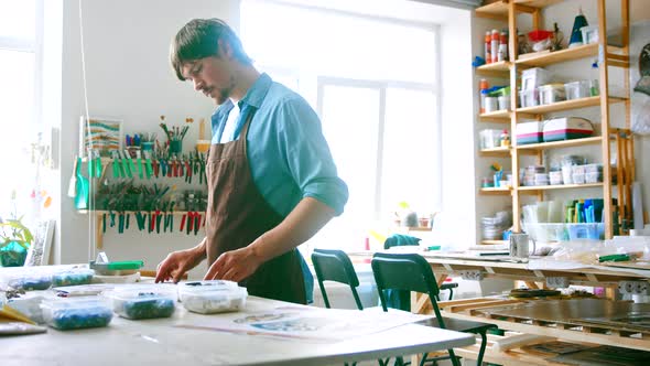 Young master in uniform looking at art sketches