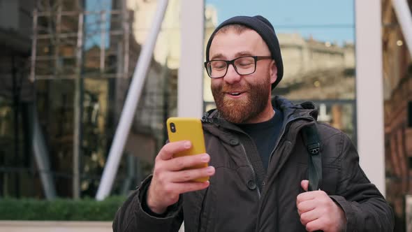 Happy Man in Glasses Looking Excited and Smiling While Walking at Street. Bearded Guy Having Good