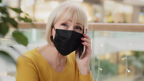 Closeup Mature Serious Caucasian Businesswoman in Medical Mask Talking on Phone Answering Mobile