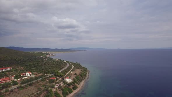 Aerial Scene of Sea, Coast with Green Hills and Houses Trikorfo Beach, Greece