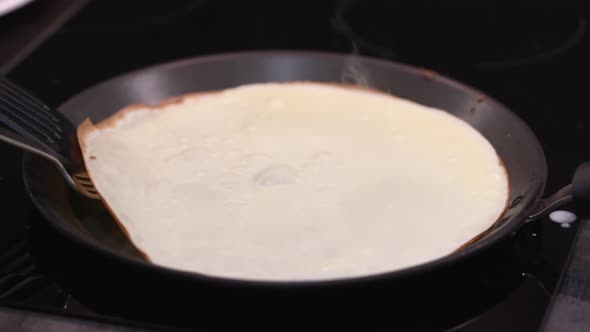 The Woman Turns the Pancake Over in the Pan