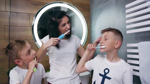 Mother and Her Sons in Homewear Carefully Cleaning Teeth with Brushes in the Bathroom
