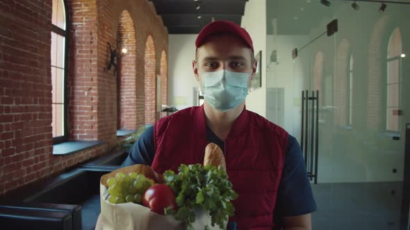 Postman or Delivery Man in Mask During Coronavirus Carry Small Box Food Deliver to Young Woman