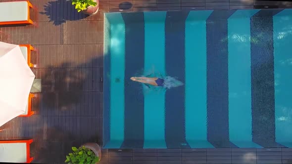 Top View of a Woman Jumping Into the Pool. Girl Wears Blue Swimsuit.