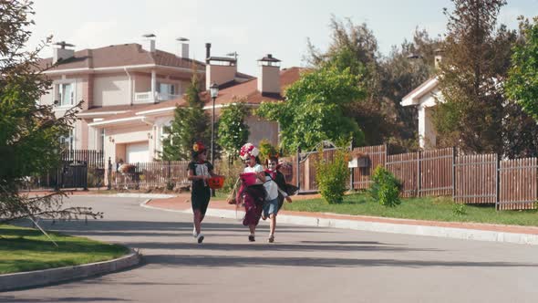 Happy Little Friends in Halloween Costumes Running Outdoors