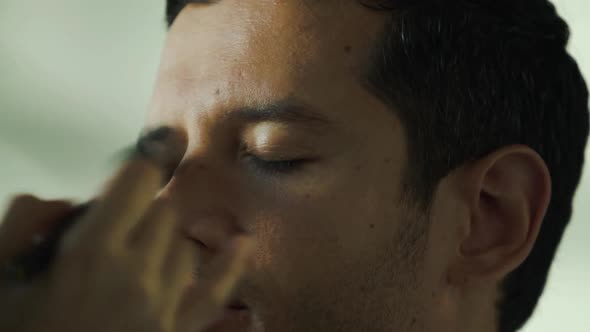 Male model getting makeup done by makeup artist