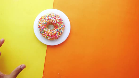 Hand Pick Fresh Colorful Donuts on Color Background