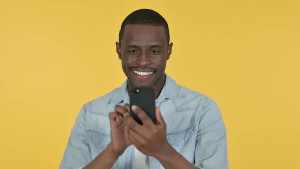 Young African Man Using Smartphone, Yellow Background 