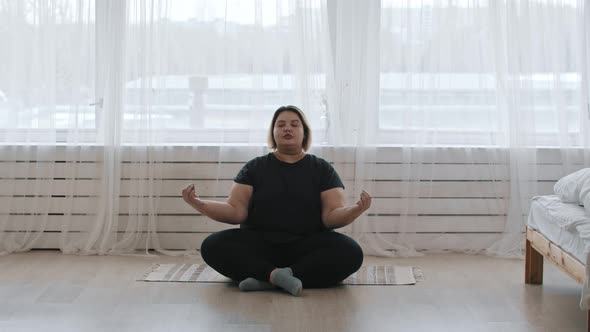 A Fat Woman Sitting in the Lotus Position at Home