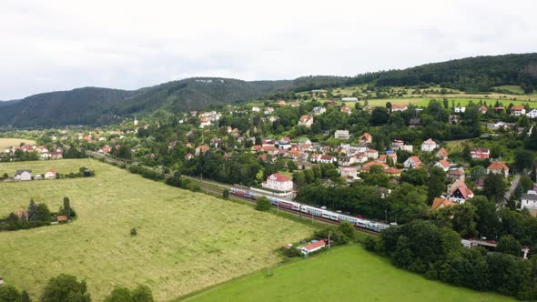 Aerial Drone Shot  a Picturesque Town and Green Fields in a Hilly Rural Area  Drone Turns to Left