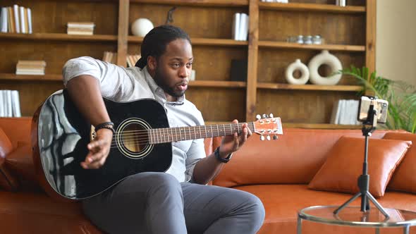 An AfricanAmerican Man Playing Guitar in Front of a Smartphone