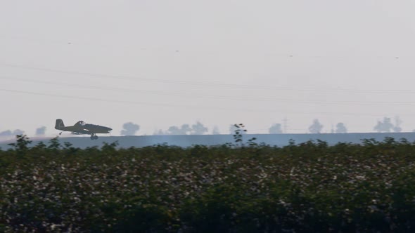 Crop duster spraying chemicals over a cotton field - slow motion