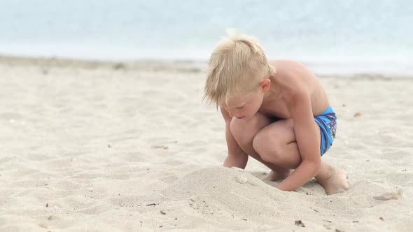 Little Blonde Boy Playing with Sand on Beach Ocean Sea