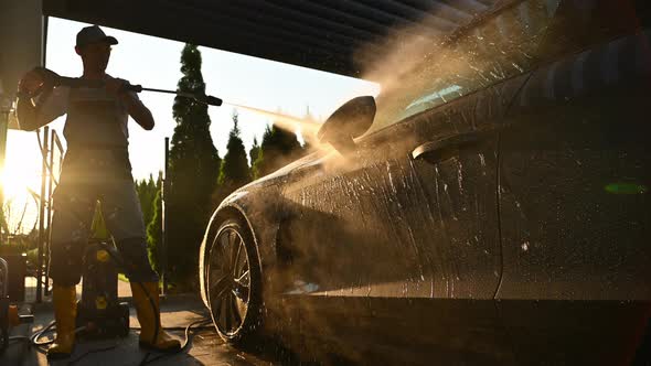 Washing Modern Luxury Car Using Powerful Pressure Washer. Automotive Industry.