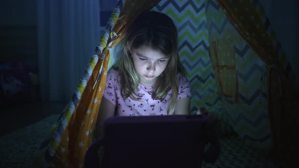 Girl with a Tablet in His Hands in the Evening at Home