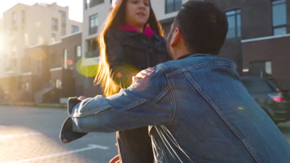 Daughter Runs To Dad and Hugs Him. Father Picks Up the Child in His Arms. Slow Motion