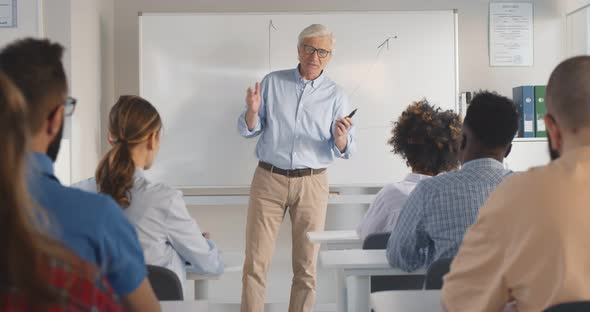 Senior Male Teacher with a Group of Students Teaching in Classroom