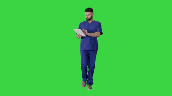 Confident Concentrated Focused Surgeon Using Digital Tablet on a Green Screen, Chroma Key.