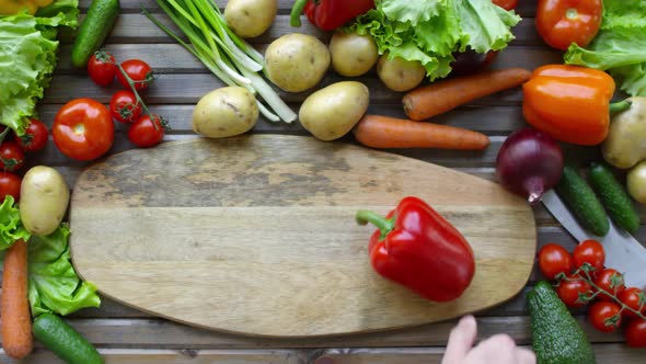 Hands of Male Cook Spinning Bell Pepper on Wooden Board with Copy Space