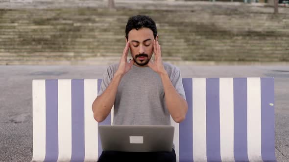 Tired Man Using Laptop on Street