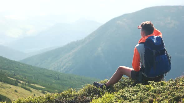 Man Hiker Sitting on Hill and Enjoying Mountains