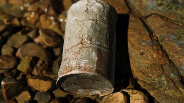 Rusty Destroyed Metal Barrel on Beach Rocks