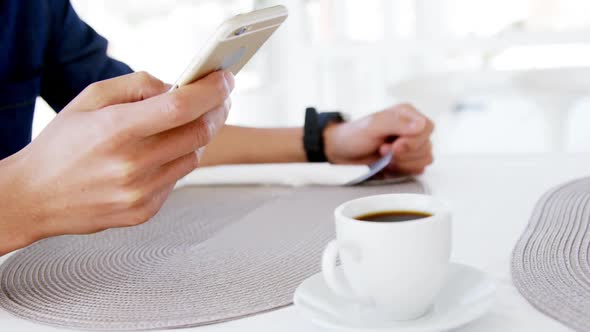 Man in lunch bar with smartphone and coffee