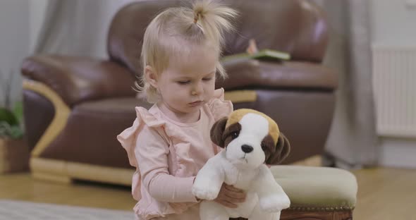 Portrait of Little Beautiful Girl Walking To Camera with Soft Toy Dog. Close-up of Charming Child