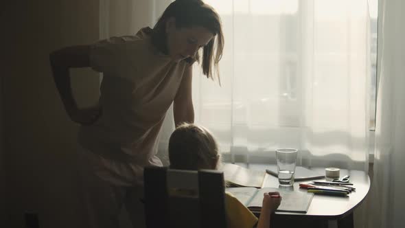 School girl doing homework with her mother at home