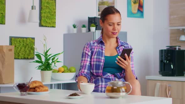 Woman Browsing on Smartphone Drinking Tea