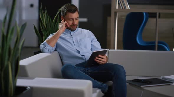 Serious Businessman Using Tablet Scrolling News Information in Modern Office