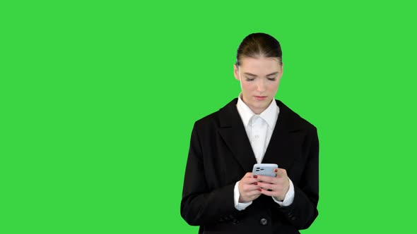 Young Female Office Worker Typing Text on Her Smartphone on a Green Screen Chroma Key