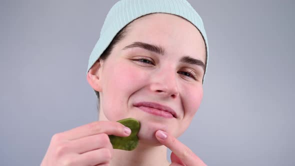 Closeup Portrait of a Young Woman Massaging Her Face with a Gouache Scraper