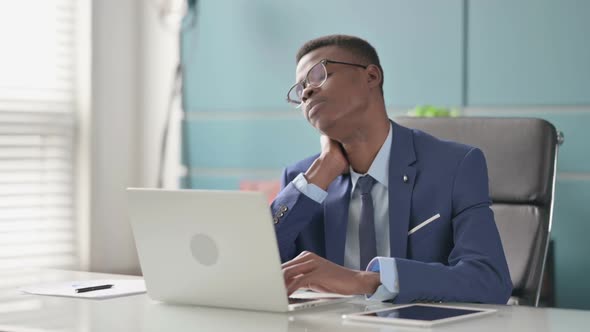 Young African Businessman Having Neck Pain While Using Laptop in Office
