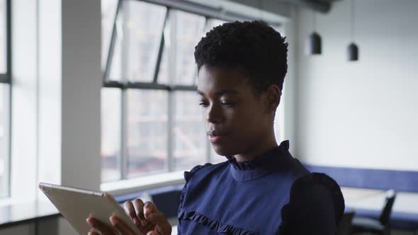 Mixed race businesswoman standing using digital tablet in office