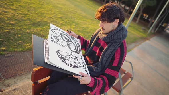 Modern Young Stylish Male Paint Artist Drawing Sketches in Park