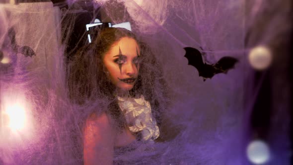 Portrait of a Woman. Girl Looks in the Mirror. The Mirror Is Decorated with Cobwebs and Bats. Model