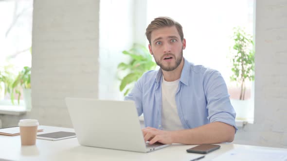 Creative Man with Laptop Feeling Shocked in Modern Office