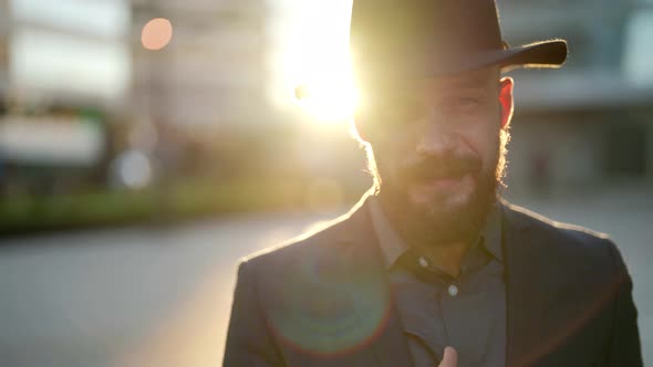 Closeup of the Face of a Smoking Bearded and Mustachioed Man in a Hat in the Contoured Sunlight